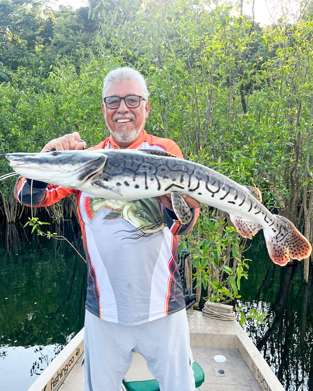 Guia de pesca com tucunaré capturado no Rio Acari