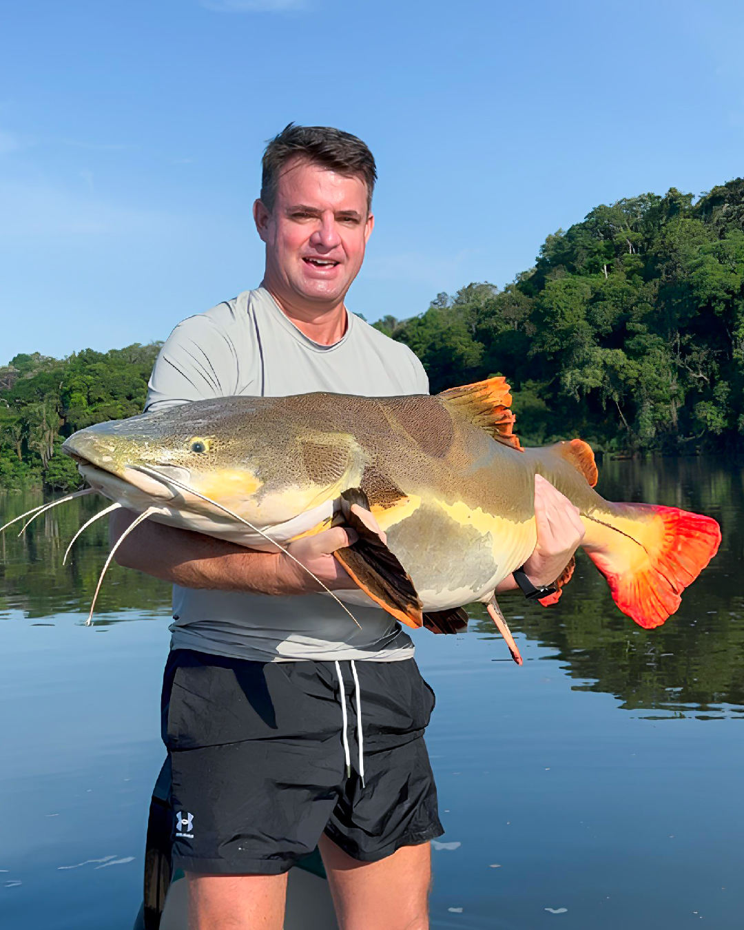 Guia de pesca com tucunaré capturado no Rio Acari